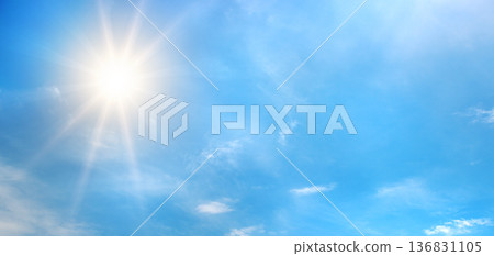 Atmospheric sky view with sunlight radiating outward and white clouds drifting across open space Atmospheric sky view with sunlight radiating outward and white clouds drifting across open space 136831105