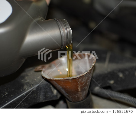 Oil change in the engine of the car. Filling the oil through the funnel. Car maintenance station. 136831670