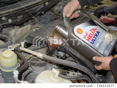 Oil change in the engine of the car. Filling the oil through the funnel. Car maintenance station. 136831677