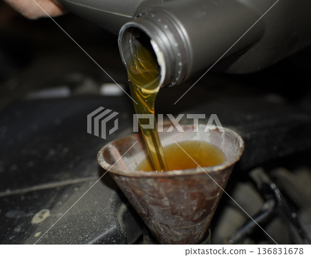 Oil change in the engine of the car. Filling the oil through the funnel. Car maintenance station. Oil change in the engine of the car. Filling the oil through the funnel. Car maintenance station. 136831678