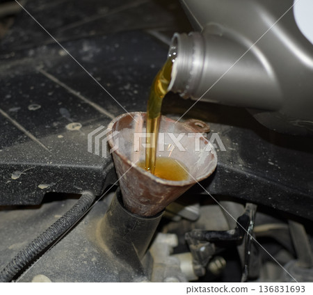 Oil change in the engine of the car. Filling the oil through the funnel. Car maintenance station. Oil change in the engine of the car. Filling the oil through the funnel. Car maintenance station. 136831693