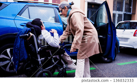 Caregiver helping person with reduced mobility getting into car Caregiver helping person with reduced mobility getting into car 136832333