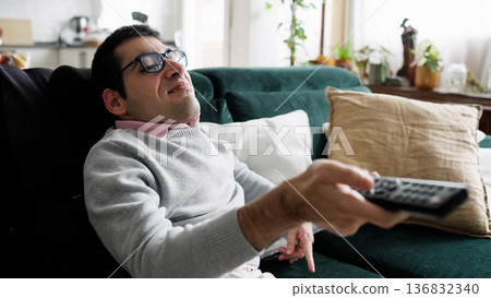 Young man relaxing on sofa watching television 136832340