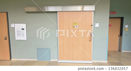 Modern sliding door in hospital corridor with safety warning sign Modern sliding door in hospital corridor with safety warning sign 136832857