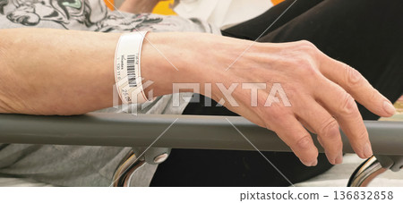 Patient's hand with hospital wristband resting on bed rail in medical setting Patient's hand with hospital wristband resting on bed rail in medical setting 136832858