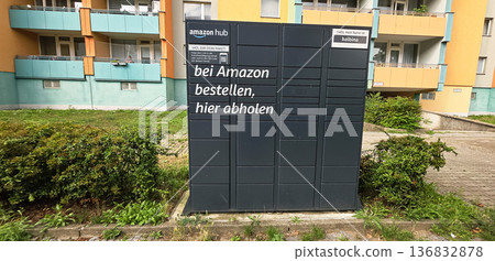 Berlin, Germany - July 14, 2025: Amazon Hub package locker in residential area with green surroundings 136832878