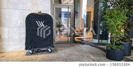 Berlin, Germany - July 17, 2025: Hotel luggage cart with logo parked outside entrance in modern setting Berlin, Germany - July 17, 2025: Hotel luggage cart with logo parked outside entrance in modern setting 136832884