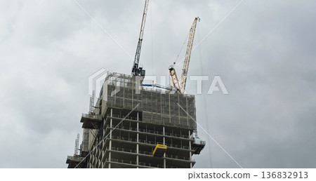 Berlin, Germany - September 17, 2025: Construction site with cranes working on high-rise building under cloudy sky Berlin, Germany - September 17, 2025: Construction site with cranes working on high-rise building under cloudy sky 136832913