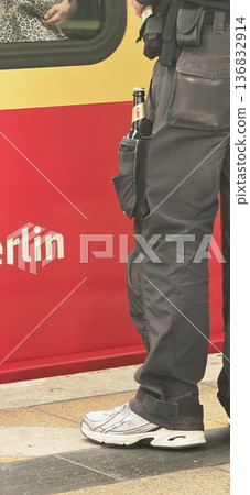 Berlin, Germany - September 17, 2025: Police officer standing near train with beverage in pocket in Berlin 136832914