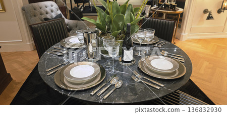 Berlin, Germany - September 19, 2025: Elegant dining table setting with glassware and decorative plant centerpiece Berlin, Germany - September 19, 2025: Elegant dining table setting with glassware and decorative plant centerpiece 136832930