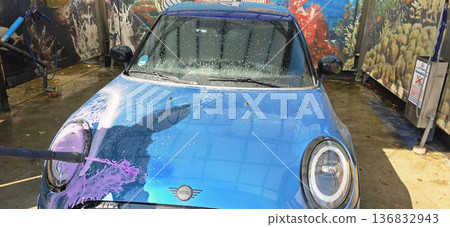 Berlin, Germany - September 27, 2025: Mini Cooper being washed at car wash with colorful background Berlin, Germany - September 27, 2025: Mini Cooper being washed at car wash with colorful background 136832943