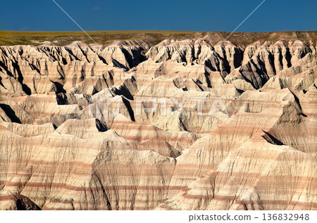 Big Badlands Overlook in Badlands National Park, South Dakota. Scenic landscape features vast eroded layered rock formations of the Badlands Wall under a blue sky 136832948