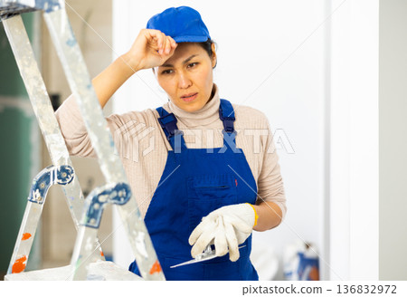 Portrait of tired upset female builder in a room where repairs are being made 136832972