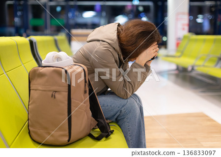 Adult caucasian woman sitting in airport waiting area feeling stressed Adult caucasian woman sitting in airport waiting area feeling stressed 136833097