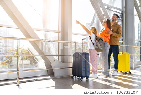 Family of three watching airplanes through airport window Family of three watching airplanes through airport window 136833107