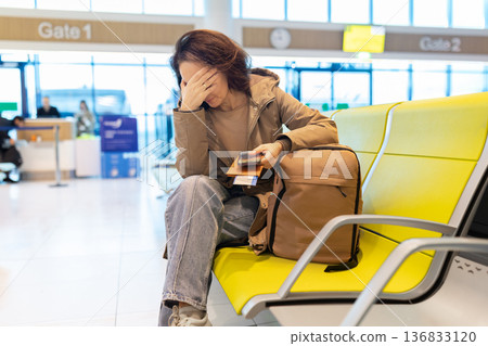 Tired caucasian woman sitting in airport terminal covering face with hand 136833120