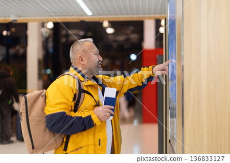 Adult caucasian man checking flight information screen in airport terminal Adult caucasian man checking flight information screen in airport terminal 136833127