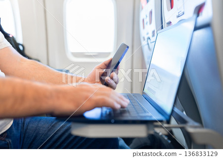 Close up of male hands typing on laptop during airplane flight Close up of male hands typing on laptop during airplane flight 136833129