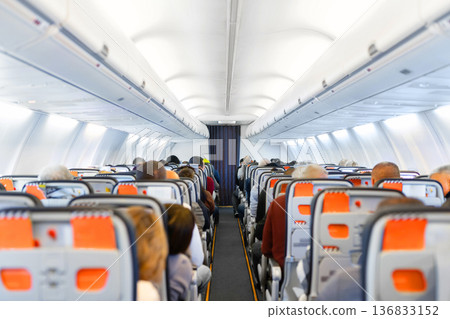 Air travel. Interior of airplane cabin with seated passengers during flight Air travel. Interior of airplane cabin with seated passengers during flight 136833152