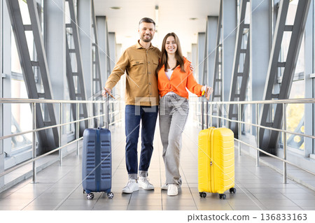 Young couple walking at airport with luggage, smiling and ready for travel 136833163