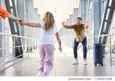 Excited daughter running to father with open arms in airport corridor 136833166