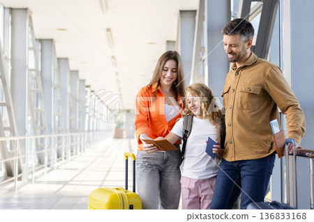Family of three at airport checking passports before flight 136833168