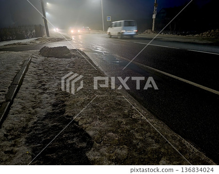Snow covered Road at Night With Cars Driving Through Fog and Darkness 136834024