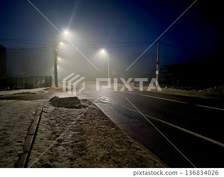Night Road Covered in Snow With Streetlights Shining in the Fog 136834026