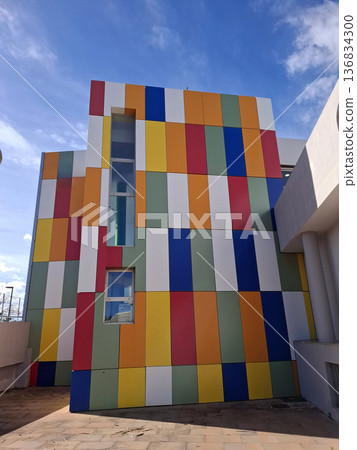 A creative building shows vibrant vertical panels in varying colors. The design features rectangular shapes and stands out against a clear blue sky. A creative building shows vibrant vertical panels in varying colors. The design features rectangular shapes and stands out against a clear blue sky. 136834300