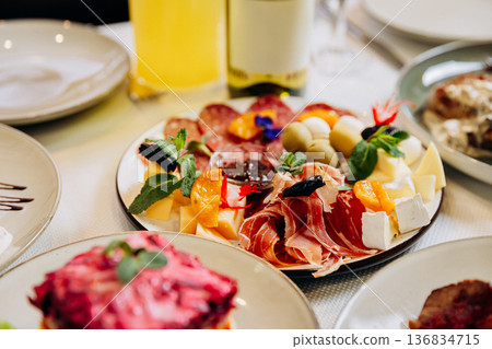 Cheese and meat appetizer platter served on elegant festive restaurant table Cheese and meat appetizer platter served on elegant festive restaurant table 136834715