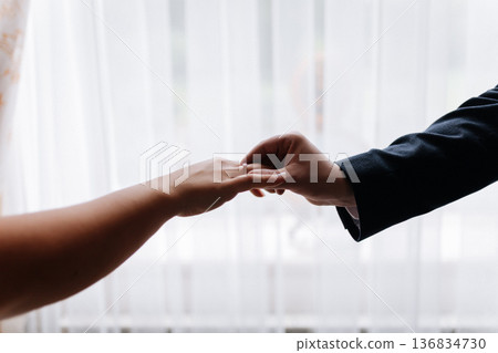 Groom placing wedding ring on brides finger during intimate marriage ceremony moment 136834730