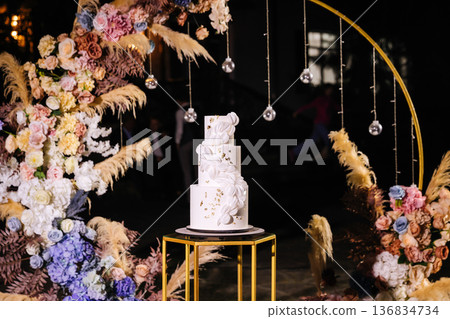 Elegant white wedding cake with floral decor at luxury reception celebration 136834734