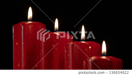 Red candles with flames shining in darkness during a quiet evening setting Red candles with flames shining in darkness during a quiet evening setting 136834822