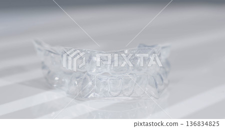 Clear dental aligner on a flat surface in a bright setting with soft shadows 136834825