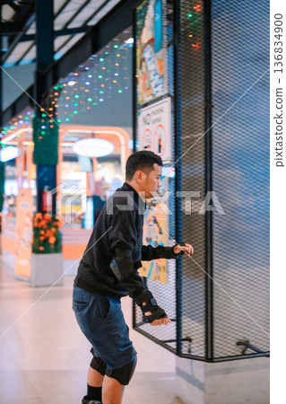 Young man enjoying roller skating indoors in a vibrant leisure space 136834900