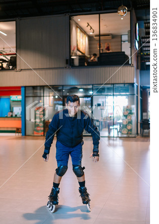 Determined Man Inline Skating in Modern Indoor Space 136834901