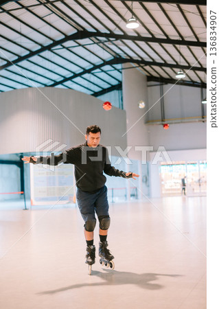 Focused Young Man Inline Skating with Protective Gear Indoors 136834907