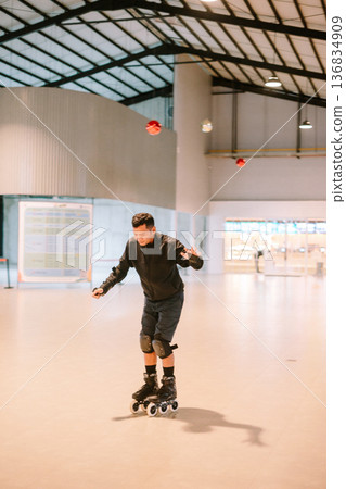 Young man enjoying inline skating activity in a modern indoor space Young man enjoying inline skating activity in a modern indoor space 136834909