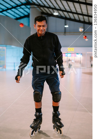 Joyful Young Man Rollerblading Inside a Modern Building 136834950