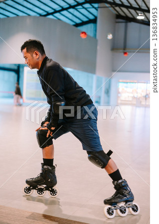 Active Young Man Inline Skating with Protective Gear Indoors 136834953