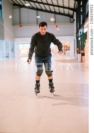 Adult man actively inline skating indoors wearing protective gear 136834955