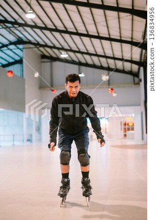 Focused man enjoying indoor rollerblading with safety equipment 136834956