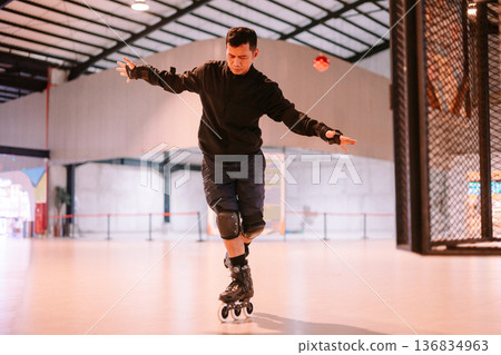 Man practicing balance while inline skating in a large indoor space Man practicing balance while inline skating in a large indoor space 136834963