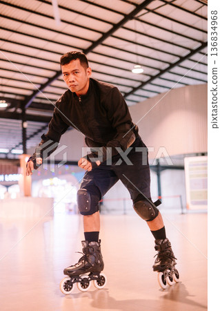 Determined Young Man Rollerblading Indoors with Protective Gear Determined Young Man Rollerblading Indoors with Protective Gear 136834968