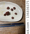Pickled plums and chopsticks arranged on a white plate 136836375