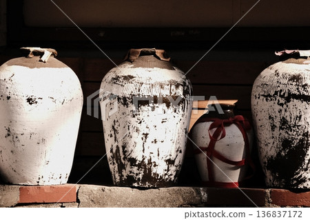 A scene conveying Chinese tradition. An empty Shaoxing wine jar. An antique sake vessel accented with a red ribbon. A scene conveying Chinese tradition. An empty Shaoxing wine jar. An antique sake vessel accented with a red ribbon. 136837172