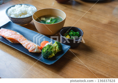 A Japanese breakfast set (grilled salmon, rice, miso soup, and natto) on a wooden table with space to the right A Japanese breakfast set (grilled salmon, rice, miso soup, and natto) on a wooden table with space to the right 136837828