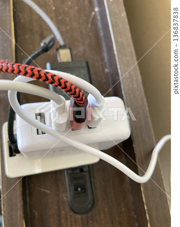 Multiple USB chargers and cables lined up on a desktop power strip 136837838