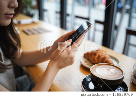 Generative AI in the hands of a woman operating a smartphone in a cafe Generative AI in the hands of a woman operating a smartphone in a cafe 136839769