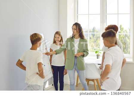 Teacher showing stand board for school children lesson, pre-teens, teenagers talking with teacher  136840567